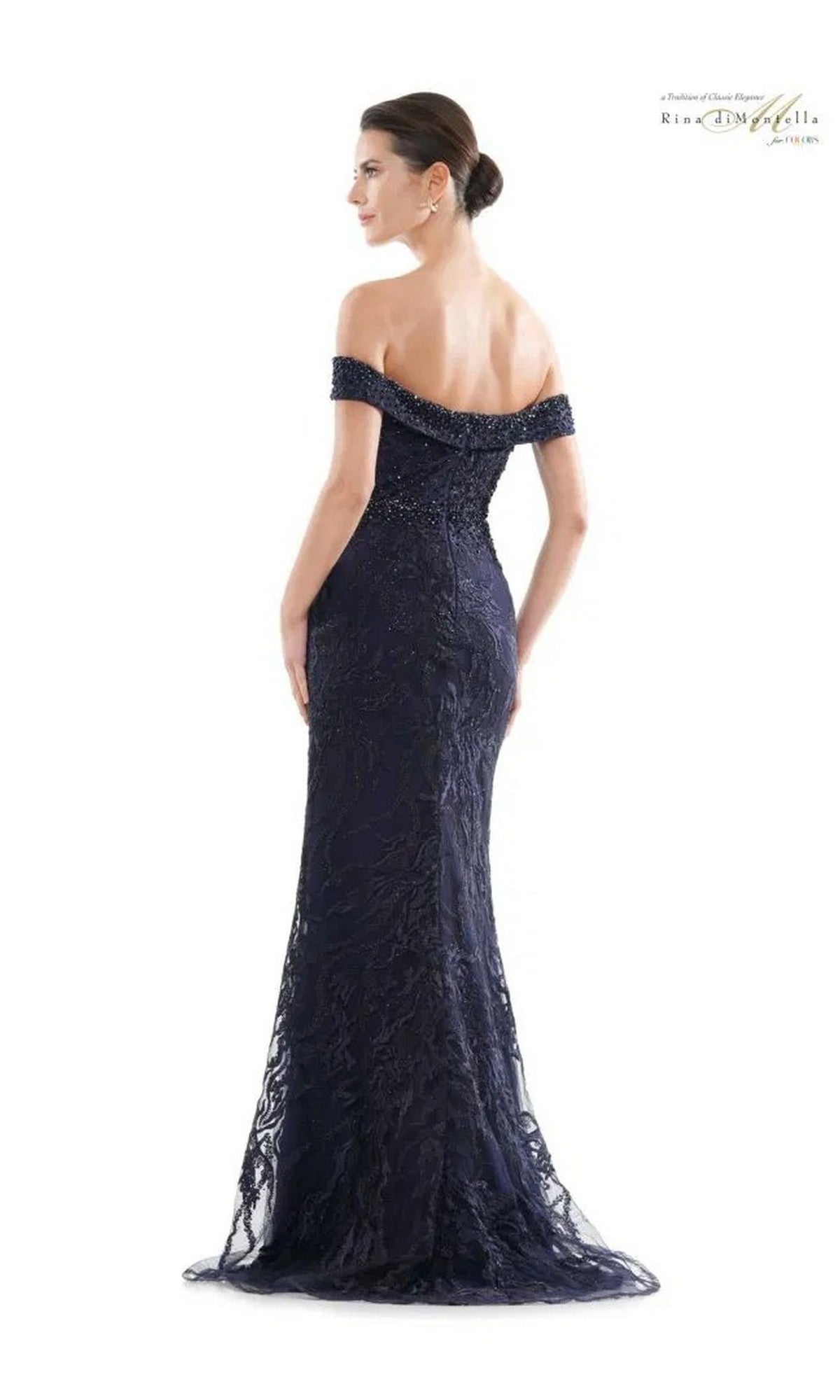 A woman in the Rina Di Montella RD2713 long formal dress—an embellished, lace-detailed gown—stands facing away from the camera.